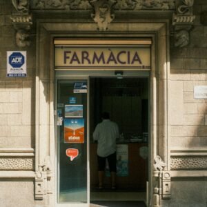 Architectural details of a historic pharmacy entrance in Madrid, Spain, featuring a lone customer inside.