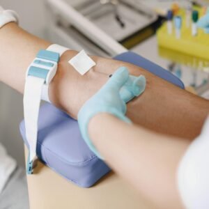Close-up of a medical professional drawing blood from a patient's arm in a clinical setting.